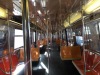an image of the interior of an R68 MTA subway car, with red and orange seats in an irregular, L-like pattern